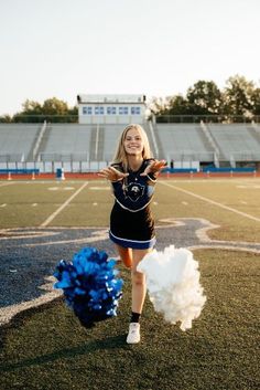 a cheerleader on the football field with her pom poms in front of her