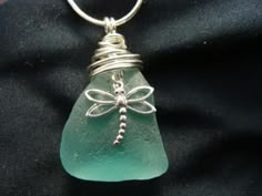 a sea glass pendant with a dragonfly on it