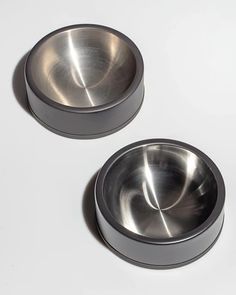 two metal bowls sitting on top of a white table