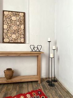 a wooden table sitting on top of a hard wood floor next to a vase and two candles