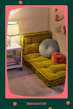 a green futon bed sitting in a living room next to a white table with a lamp on it