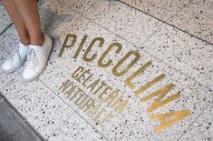 a woman standing on the sidewalk with her feet up in white tennis shoes next to an inscription that reads piccolinia beketch memorial