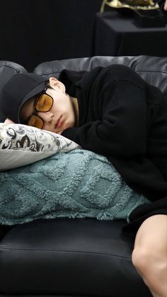 a young man laying on top of a black couch