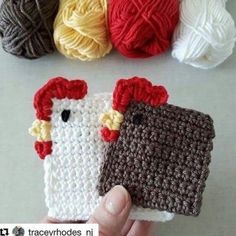 crocheted chicken applique in front of yarn balls on white surface with hand holding it