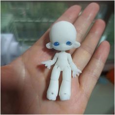 a small white doll with blue eyes sitting in someone's hand