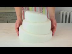 a woman is holding a stack of white cakes