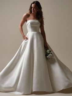 a woman in a white wedding dress standing with her hands on her hips