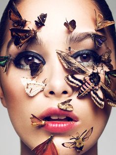 a woman's face with butterflies on it and moths all over her face,