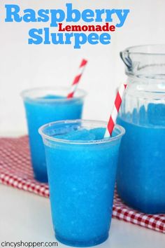 two glasses filled with blue liquid on top of a red and white checkered table cloth