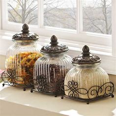 three glass jars filled with food sitting on top of a counter next to a window