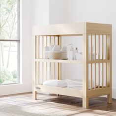 a wooden bunk bed sitting next to a window with white sheets on top of it