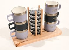 a stack of coffee mugs sitting on top of a wooden tray next to each other