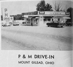 an old black and white photo of cars parked in front of a drive - in