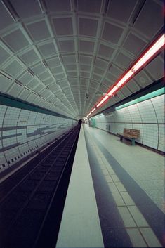 an empty subway station with benches and lights on the ceiling, as seen from inside