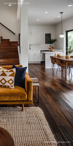 a living room filled with furniture next to a wooden flooring covered stair case in front of a kitchen