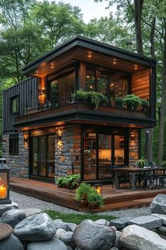 a small house with lots of windows and lights on the front, surrounded by rocks