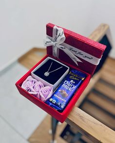 an open red box with jewelry inside sitting on a wooden bench