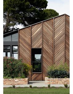 a wooden building with plants and flowers in front of the entrance to the building is made out of wood planks