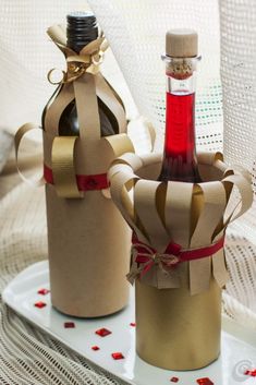 two wine bottles wrapped in brown paper and tied with red ribbon