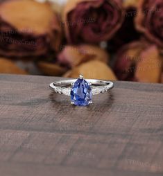 a tan and white gold ring with a blue sapphire stone in the center, surrounded by roses