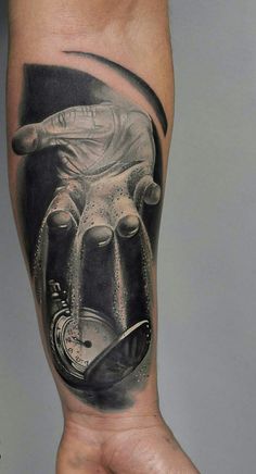 a man's arm with a black and grey tattoo on it, depicting an image of a hand holding a clock