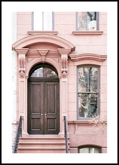 a pink building with a brown door and steps leading up to the front entrance area