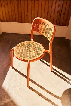 an orange chair sitting on top of a cement floor