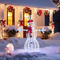 a lighted snowman in front of a house