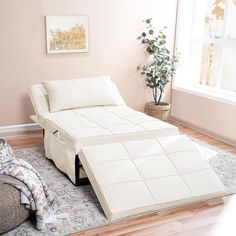 a white bed sitting on top of a hard wood floor next to a chair and window