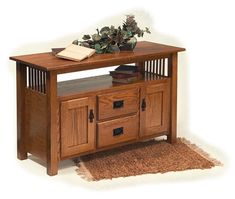 a wooden table with drawers and a plant on top, sitting next to a rug