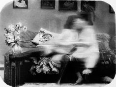 black and white photograph of a woman sitting on a couch with flowers in front of her