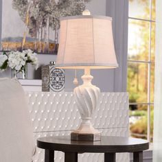 a white lamp sitting on top of a table next to a chair in a living room