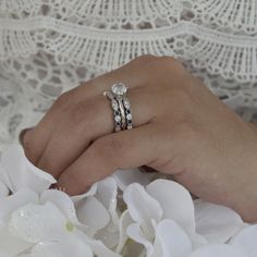 a close up of a person's hand with two wedding rings on their fingers