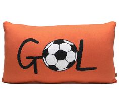 an orange pillow with a black and white soccer ball embroidered on the front that says gol