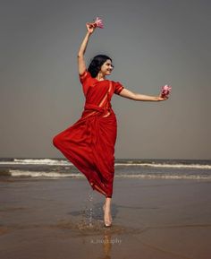 a woman in a red dress is dancing on the beach