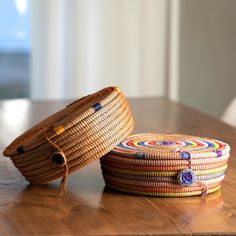 two baskets sitting on top of a wooden table next to each other, one has a rope wrapped around it