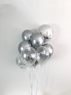 a vase filled with silver balloons on top of a table