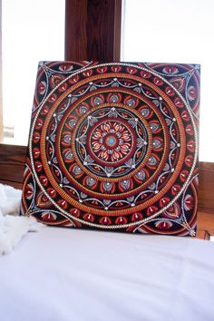 a decorative pillow sitting on top of a bed next to a wooden window sill