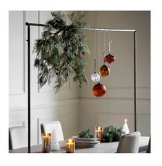 a christmas tree with ornaments hanging from it's branches in front of a dining room table