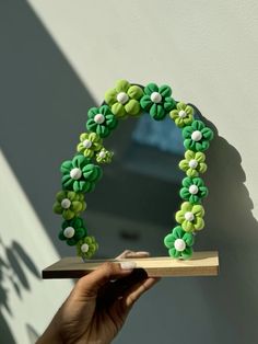 a hand holding a piece of cake in the shape of a flower arch with green and white flowers on it