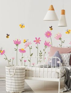 a white bed sitting under two lamps next to a wall with flowers and bees on it