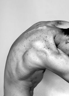 a black and white photo of a shirtless man with his hand on his head