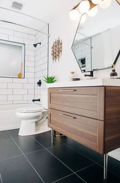 a bathroom with black tile flooring and white walls, along with a wooden cabinet