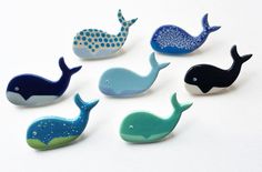 six small whale magnets sitting on top of a table next to each other in different colors