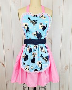 a mannequin wearing a blue and pink apron with black cats on the front