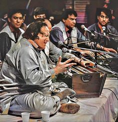 a man sitting in front of microphones on top of a table next to other men