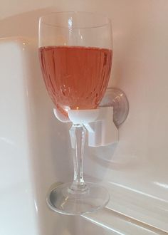 a wine glass sitting on the edge of a bathtub