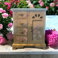 a white and gold dresser next to pink flowers