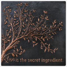 the words love is the secret ingredient on a black leather background with gold leafy branches