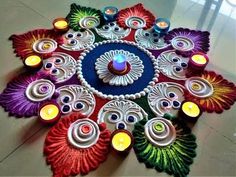 a colorful flower made out of paper with candles on it's sides and surrounded by smaller flowers